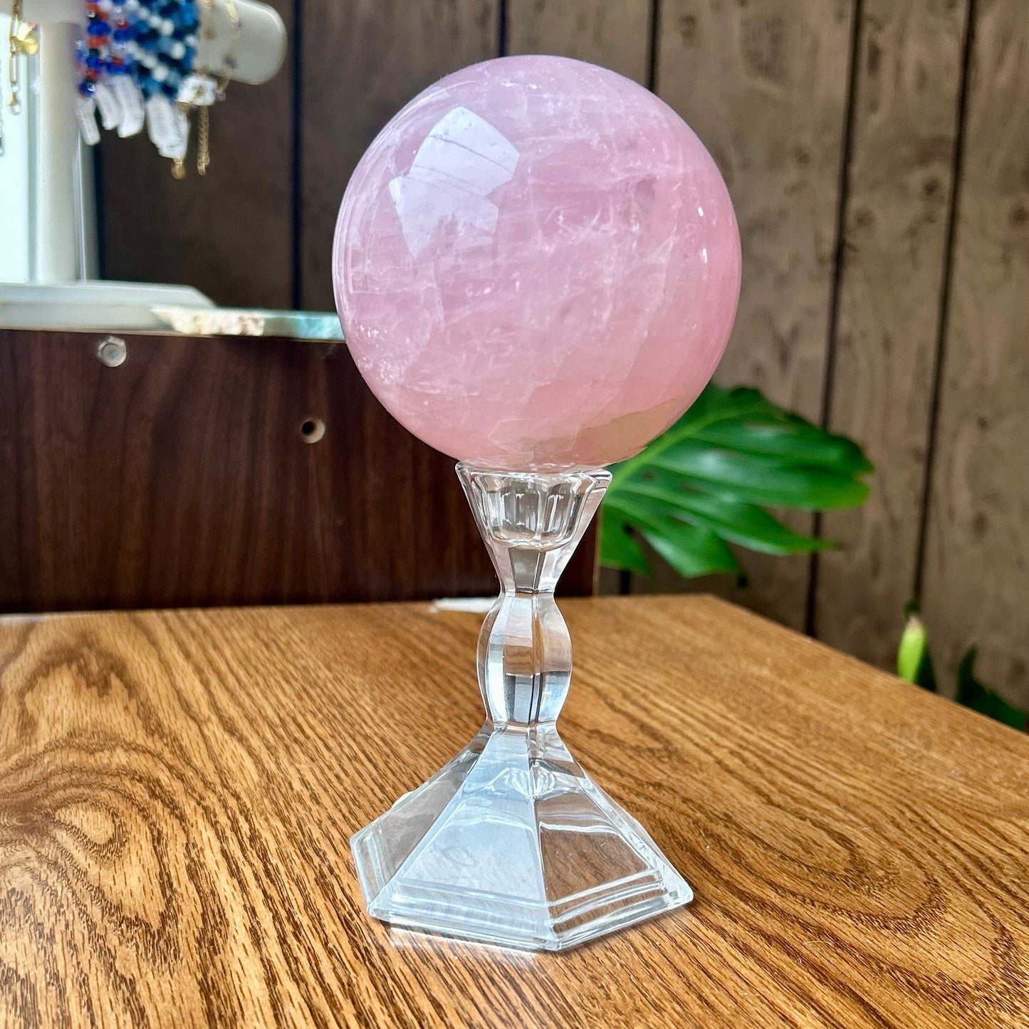 Pink crystal ball on a stand on a wooden surface