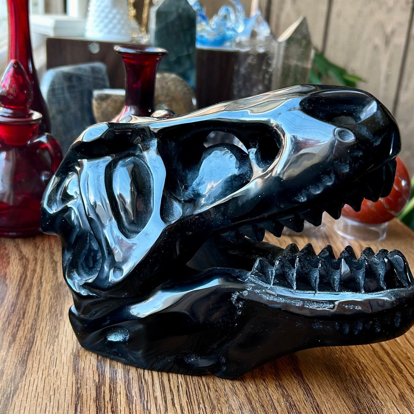 Black ceramic dragon head sculpture on a wooden surface with decorative items in the background.