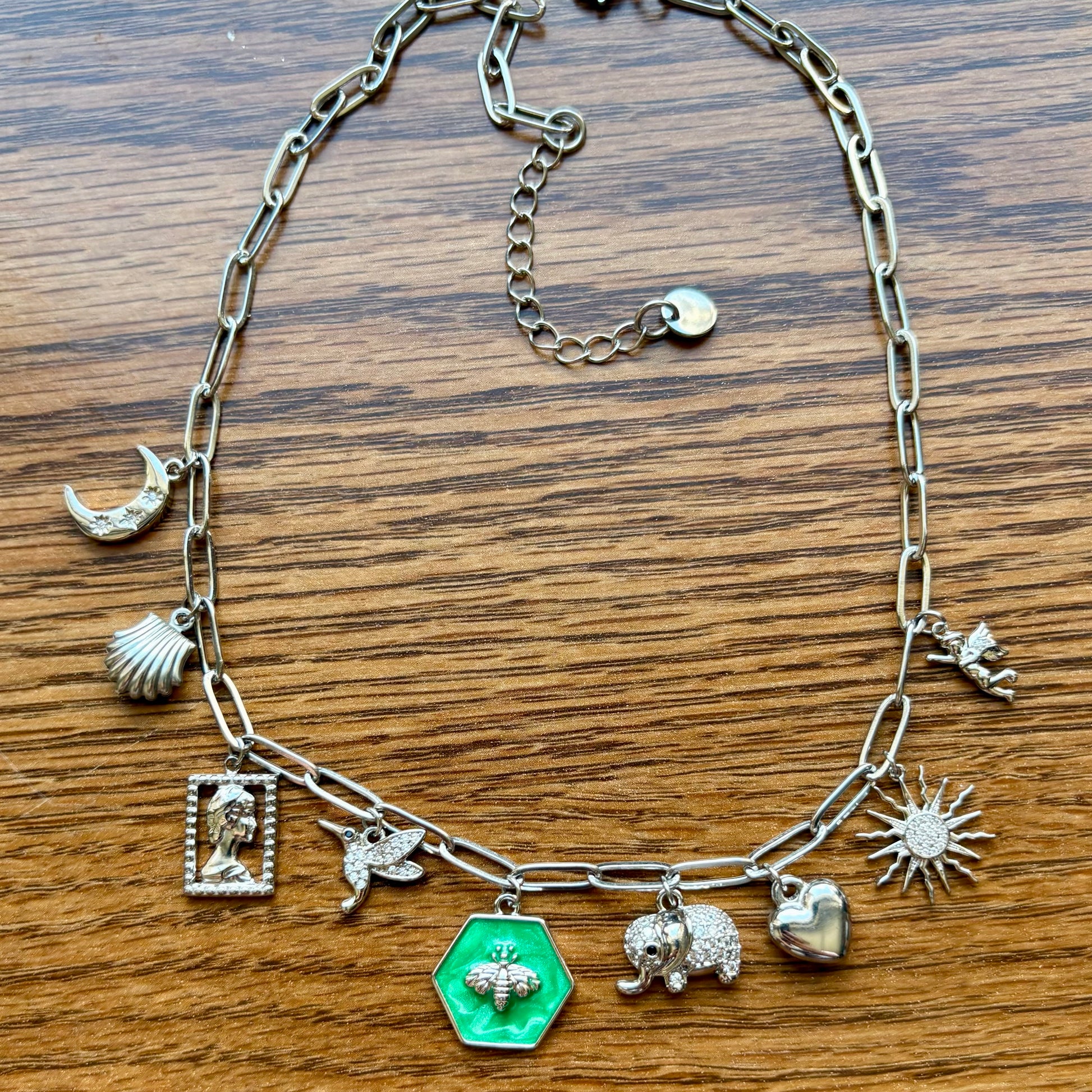Silver chain bracelet with various charms on a wooden surface