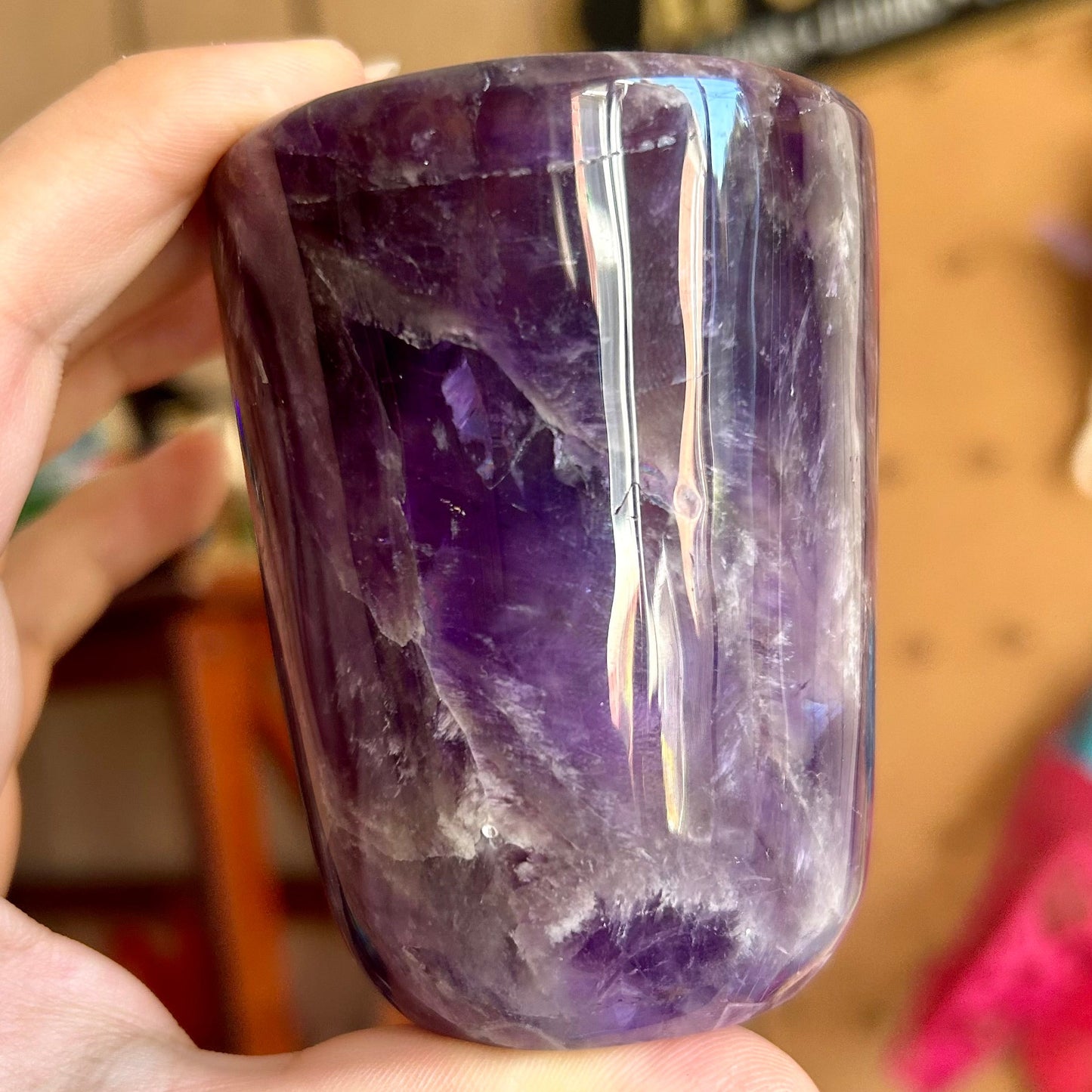 Amethyst crystal held by a hand with a blurred background