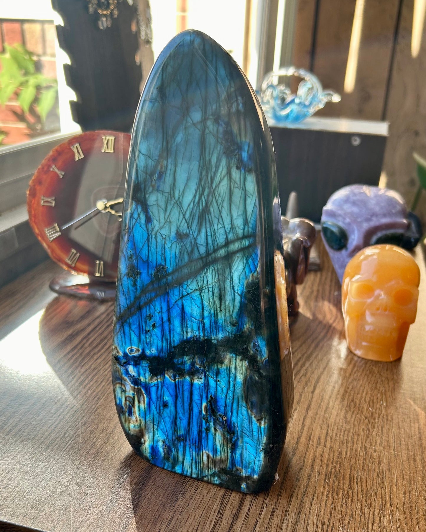 Blue and black crystal on a wooden surface with a clock and decorative items in the background