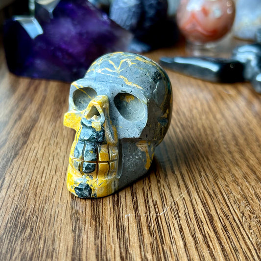 Mineral skull specimen on a wooden surface with crystals in the background