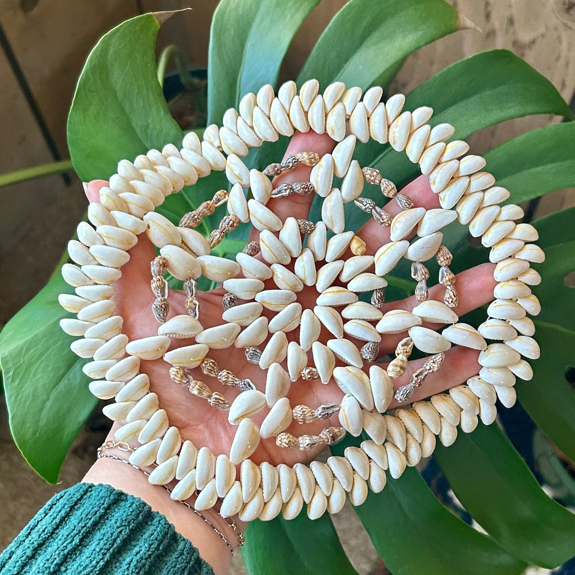 Decorative circular object with white and beige pattern held by a person against a wooden background