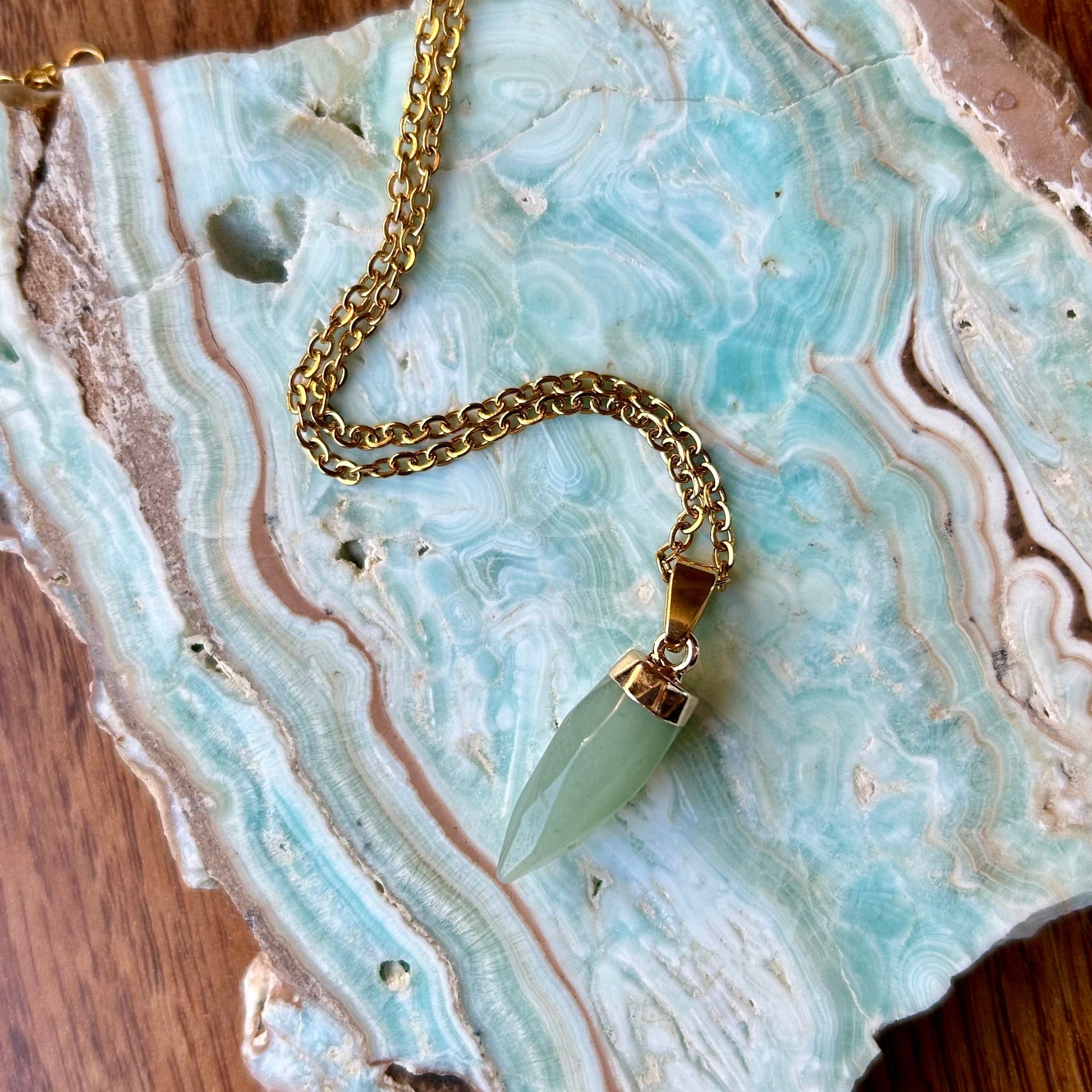 Necklace with a green pendant on a decorative stone surface