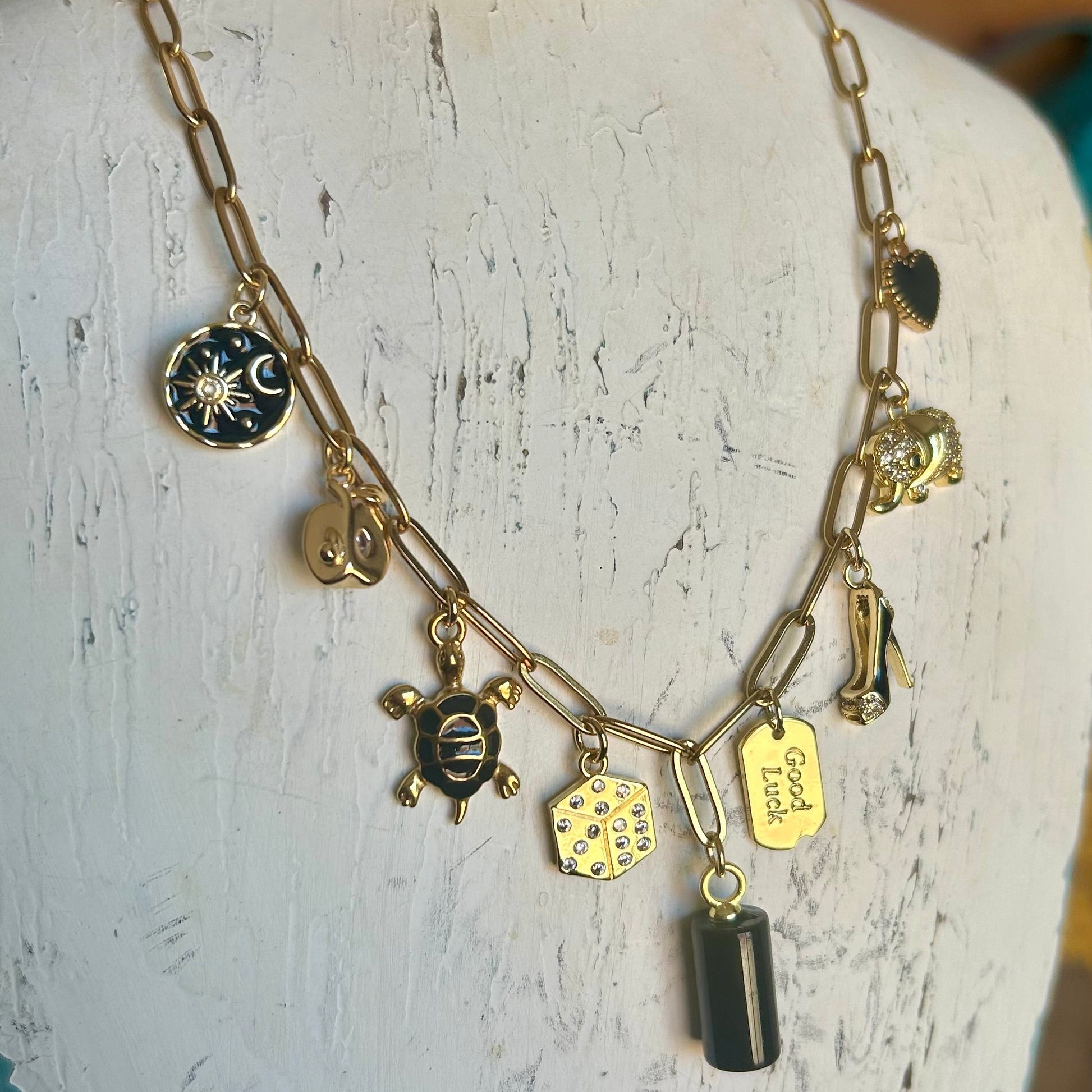 Necklace with various charms on a mannequin bust.