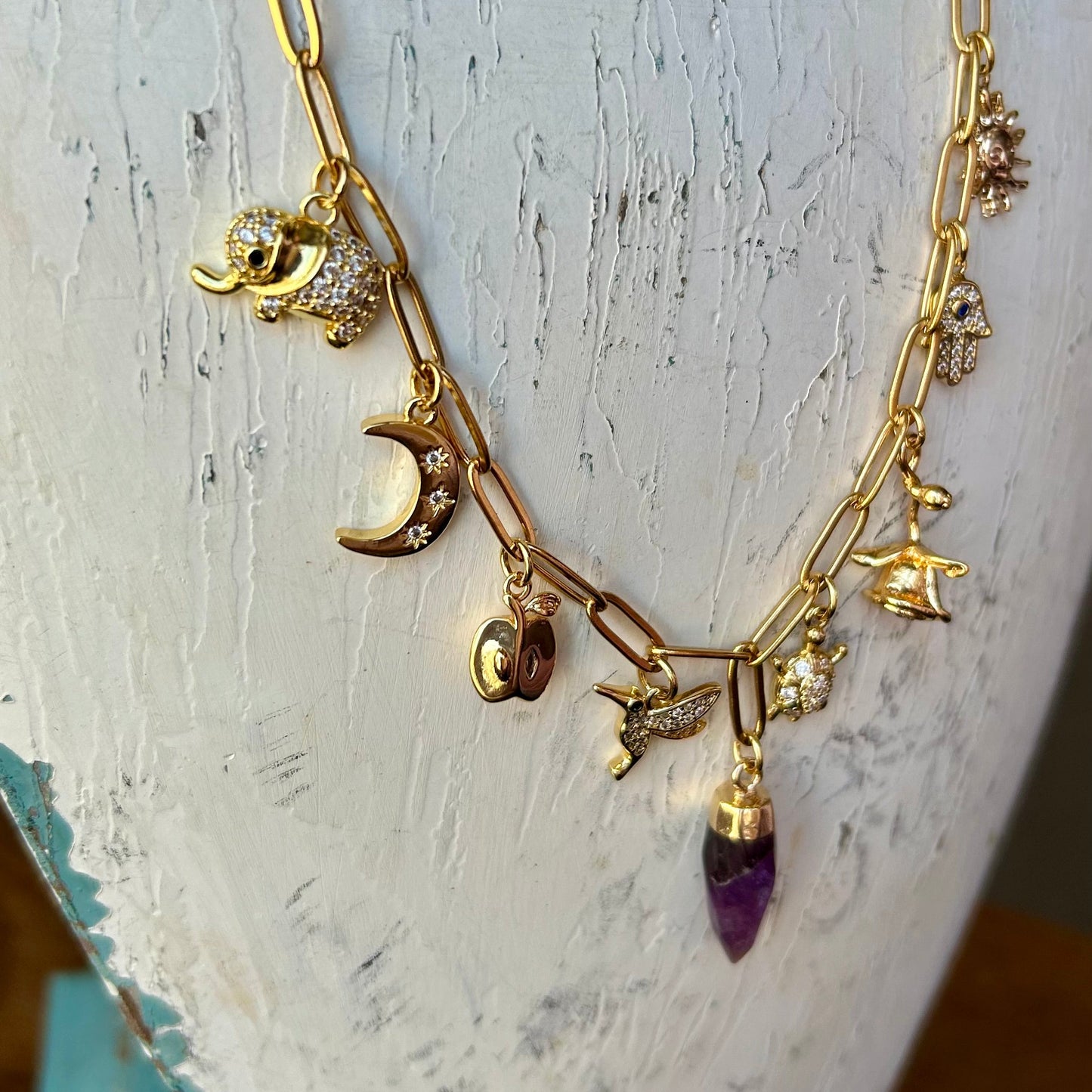 Gold necklace with charms on a mannequin bust against a white background