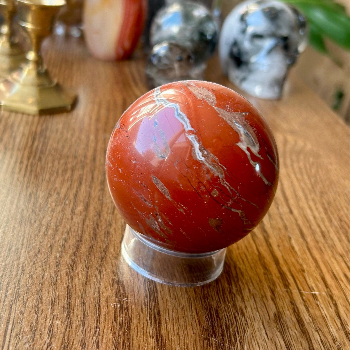Red marbled sphere on a wooden surface with decorative items in the background