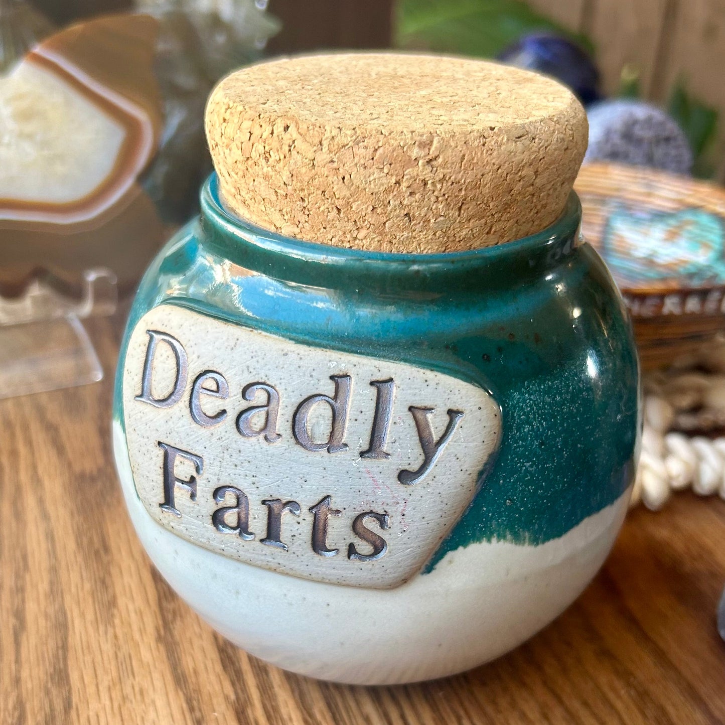 Jar labeled 'Deadly Farts' with a cork lid on a wooden surface.