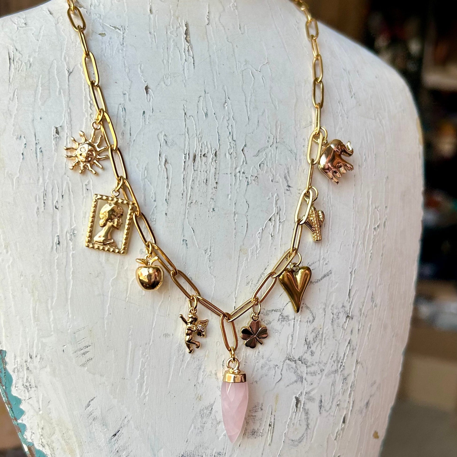 Gold necklace with charms on a mannequin bust.