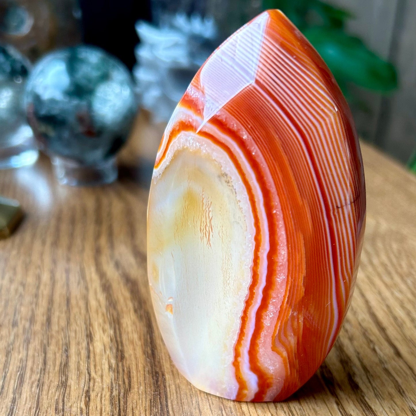 Polished agate stone with orange and white bands on a wooden surface