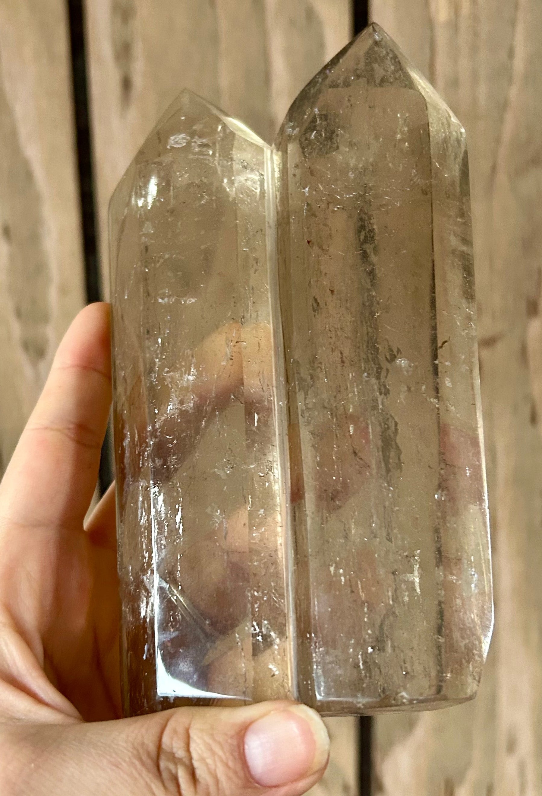 Hand holding two crystal points against a wooden background