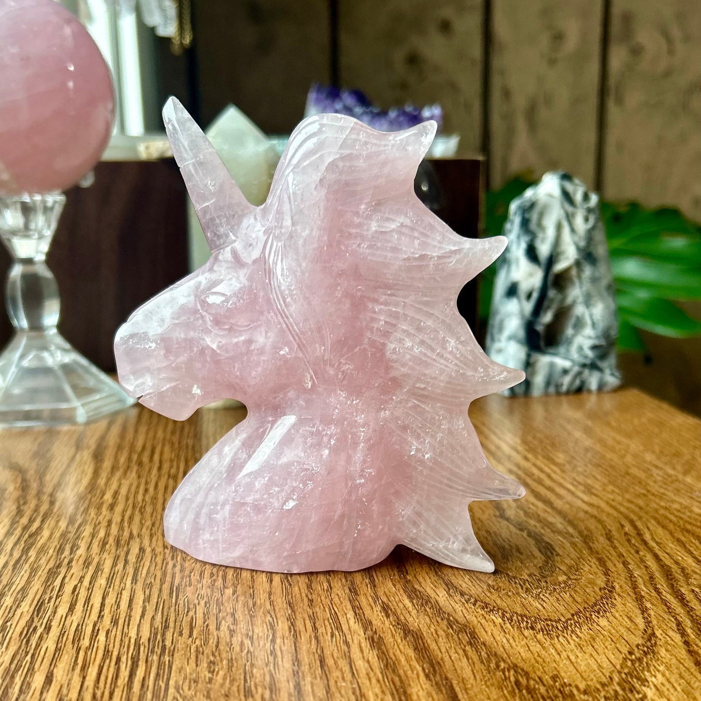 Pink crystal unicorn figurine on a wooden surface with blurred background