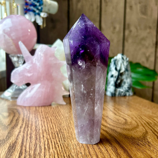 Amethyst crystal on a wooden surface with other crystals in the background