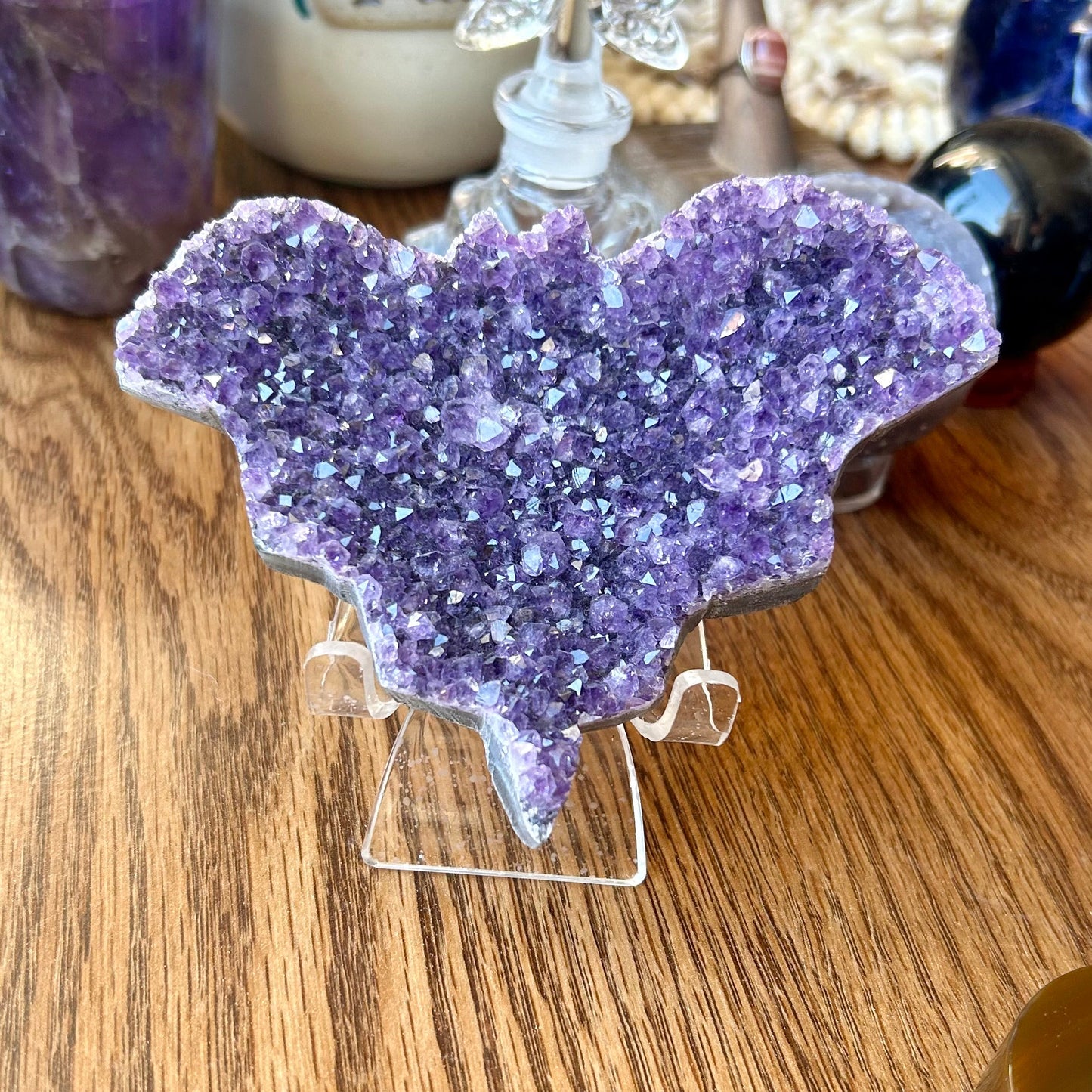 Purple crystal heart on a stand with a blurred background of decorative items.
