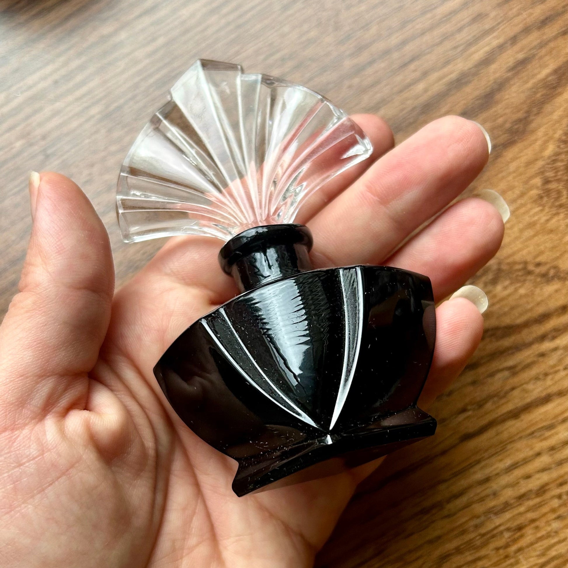 Hand holding a black and clear decorative object on a wooden surface