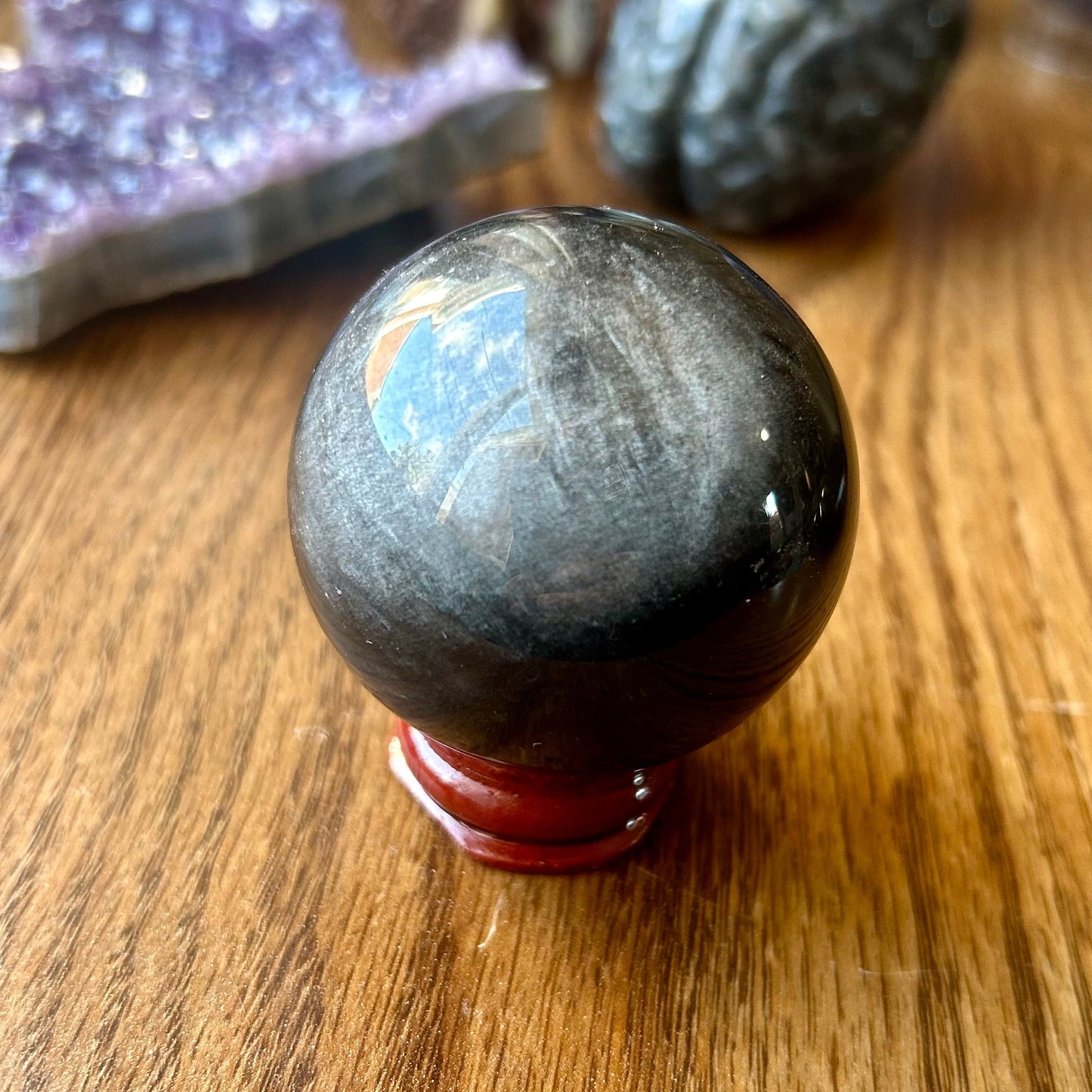 Black stone sphere on a wooden surface with crystals in the background