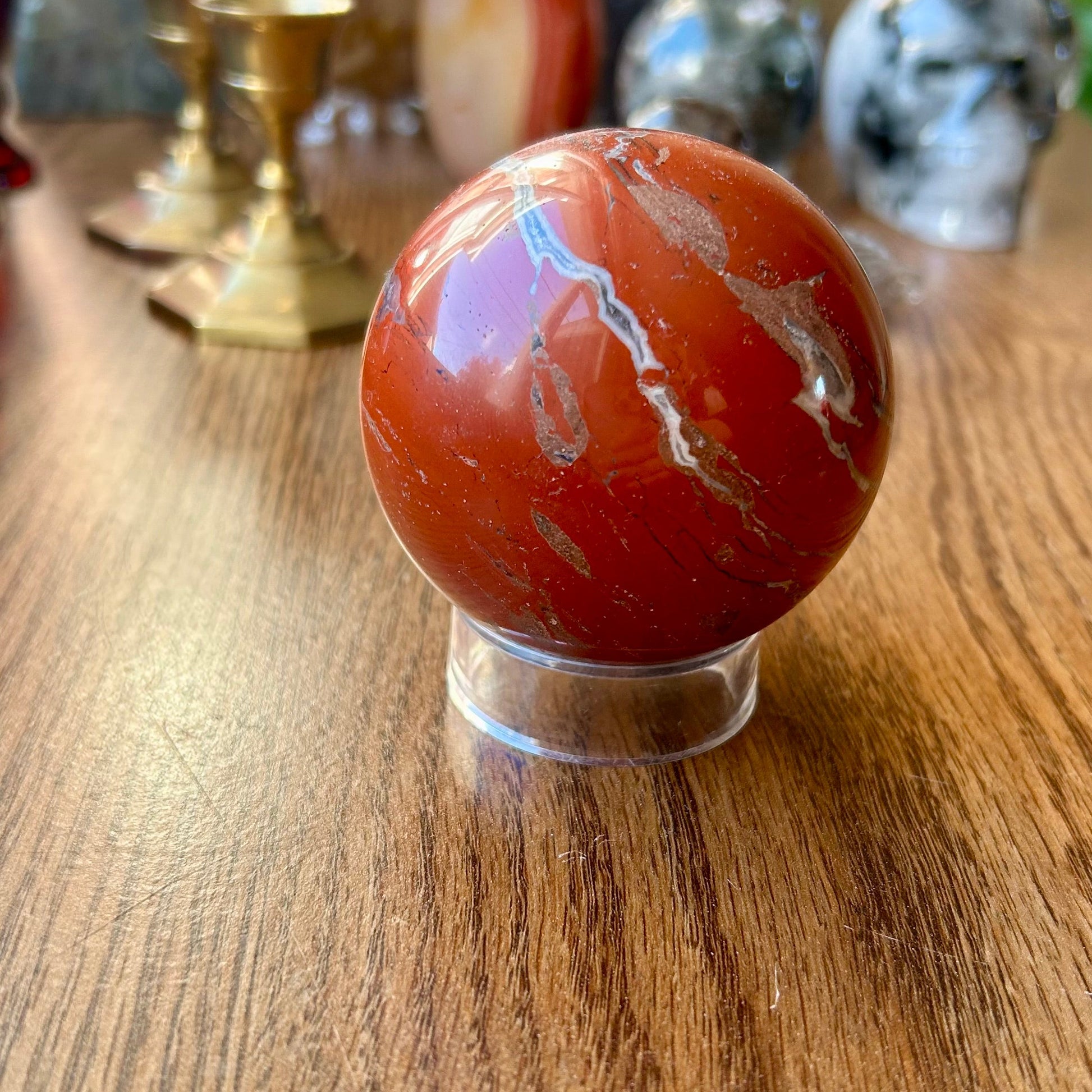 Marbled red and white sphere on a wooden surface with decorative items in the background