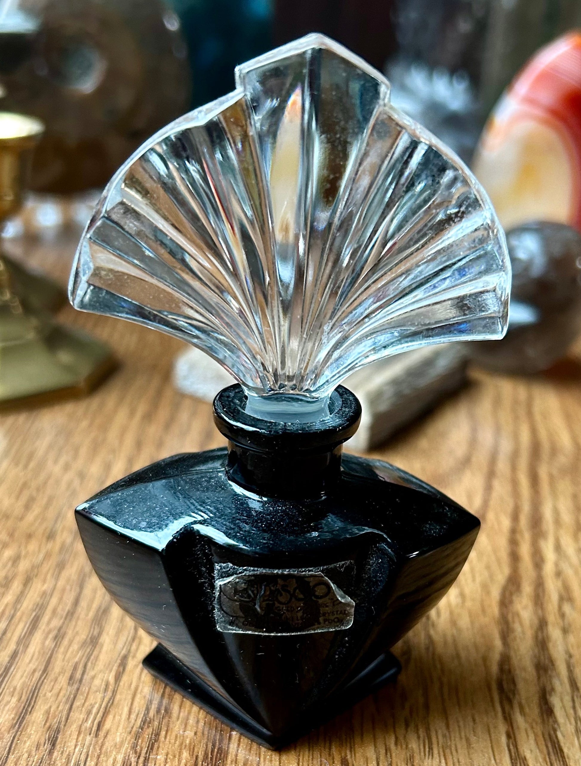 Black perfume bottle with a clear glass cap on a wooden surface