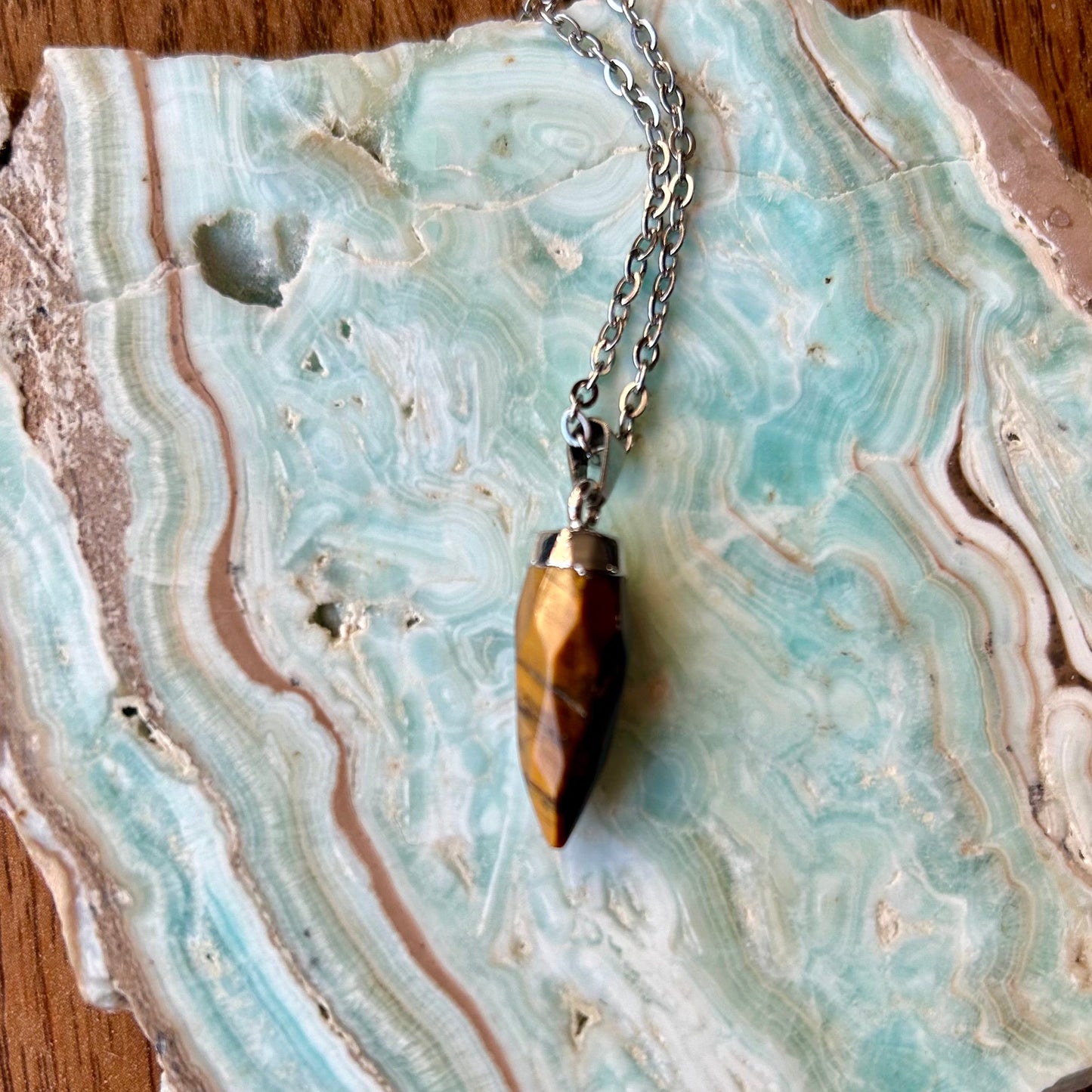 Gold arrowhead pendant necklace on a decorative stone surface