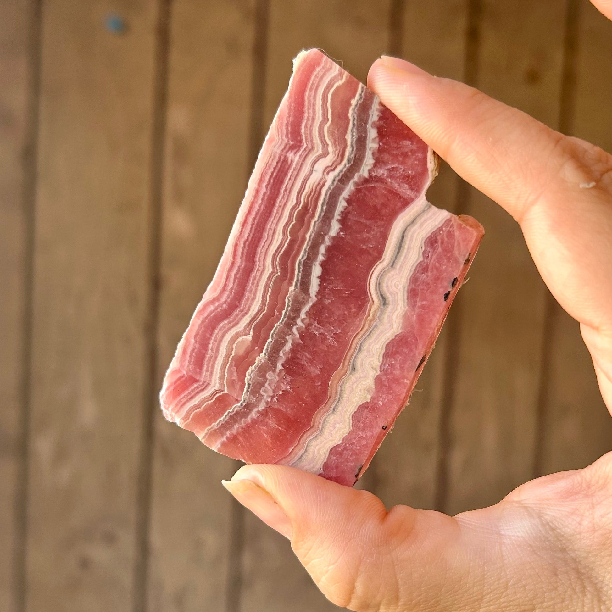 Hand holding a piece of raw meat with a wooden background