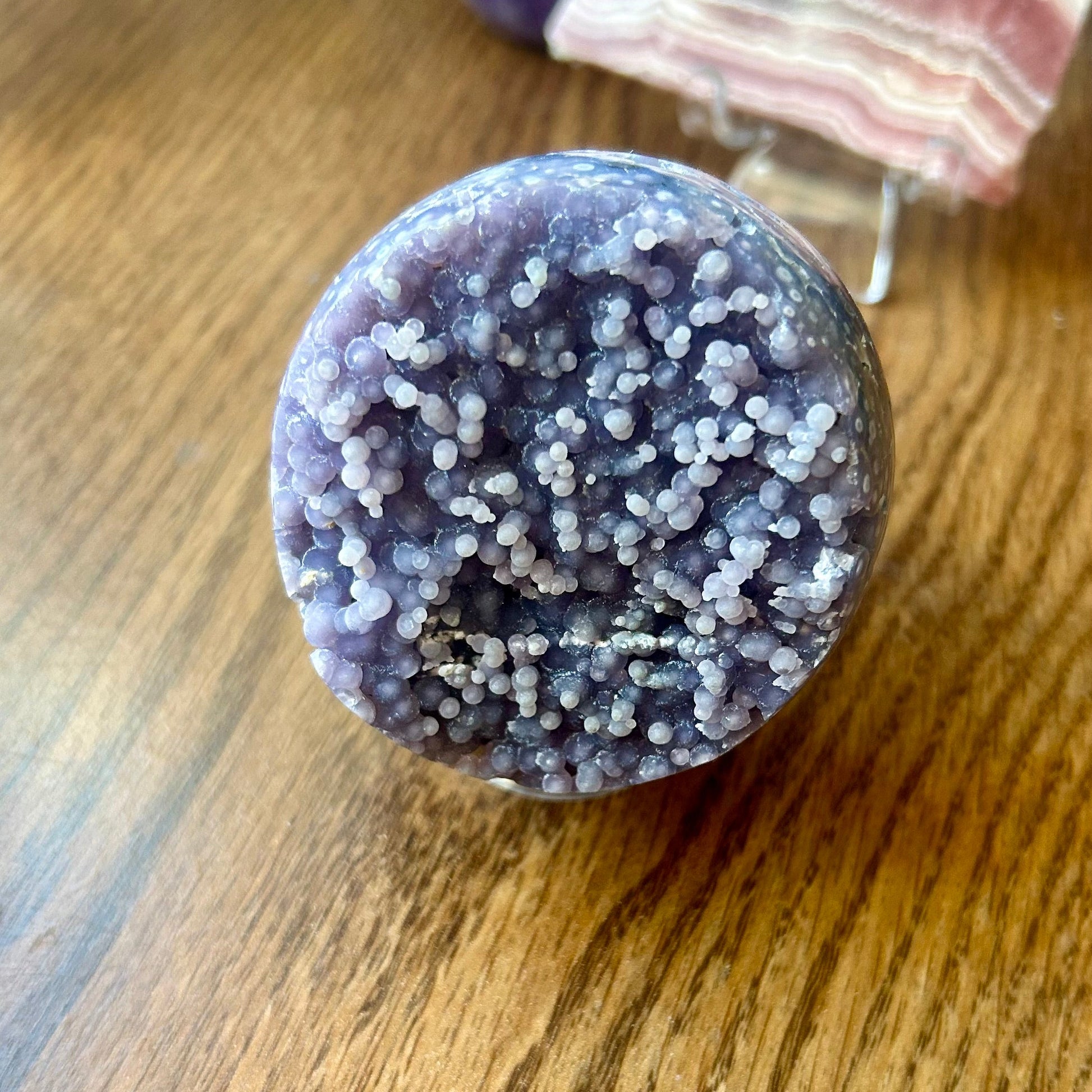 Decorative stone with purple and white speckles on a wooden surface