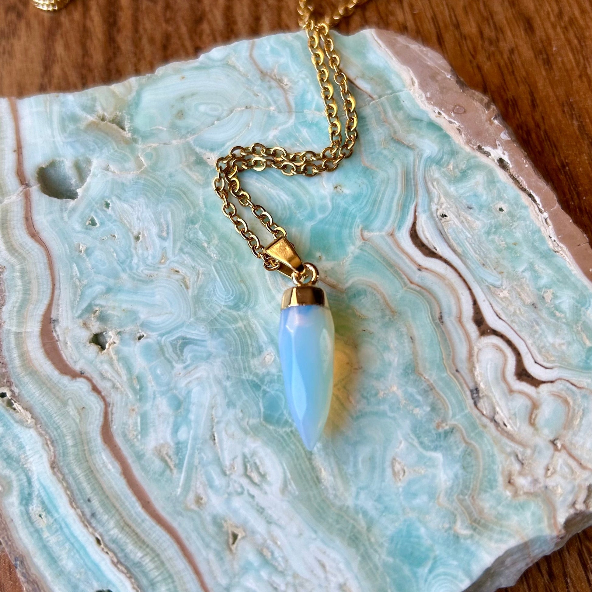 Gold necklace with a blue pendant on a decorative stone surface