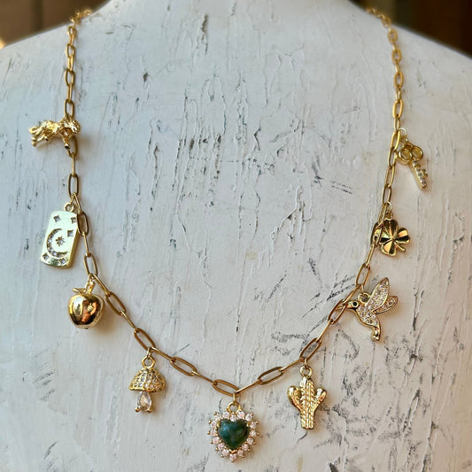 Gold necklace with various charms on a mannequin bust.