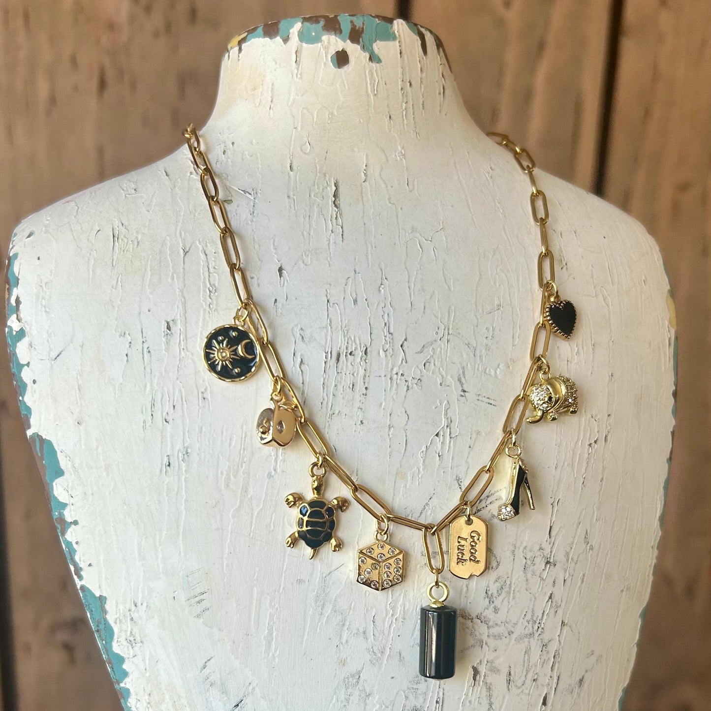 Necklace with various charms on a mannequin bust against a wooden background