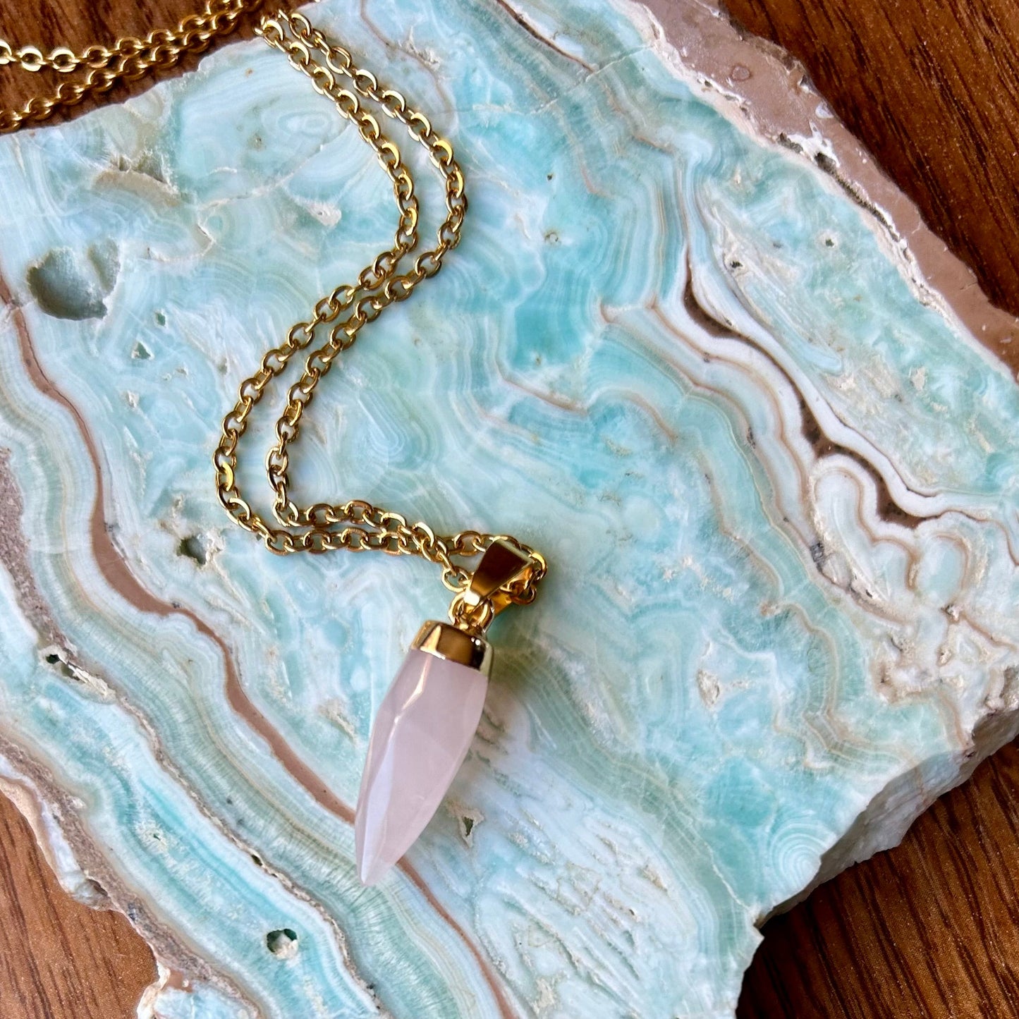 Necklace with a pink crystal pendant on a decorative stone surface