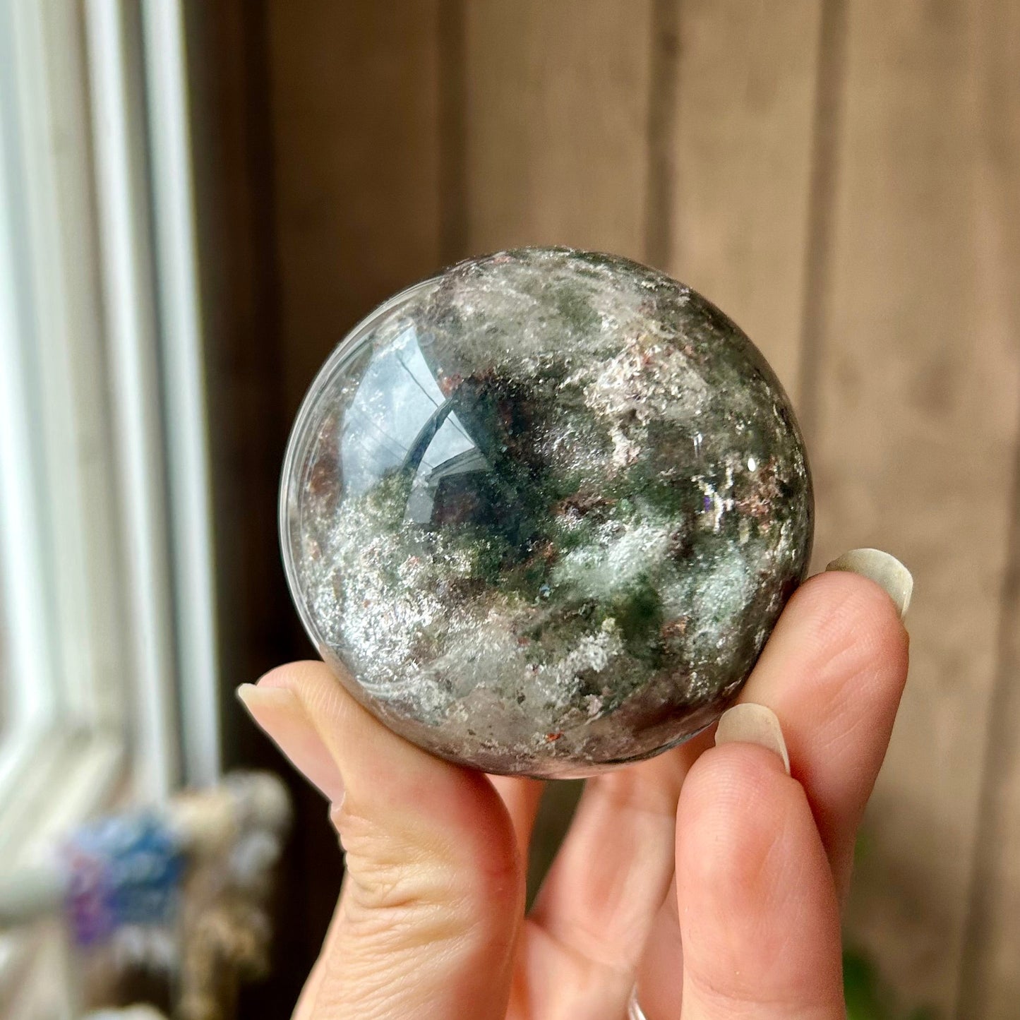 Hand holding a polished crystal ball with a neutral background