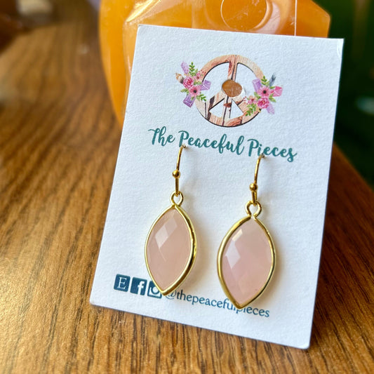 Earrings on a card with 'The Peaceful Pieces' branding on a wooden surface.
