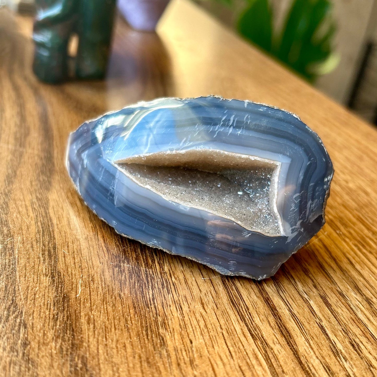 Blue crystal on a wooden surface with decorative items in the background