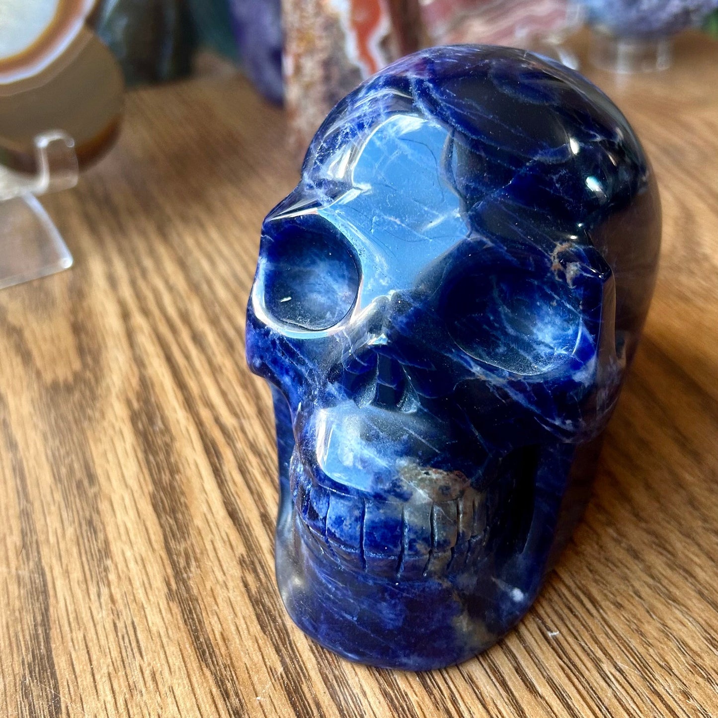 Blue crystal skull on a wooden surface with blurred background