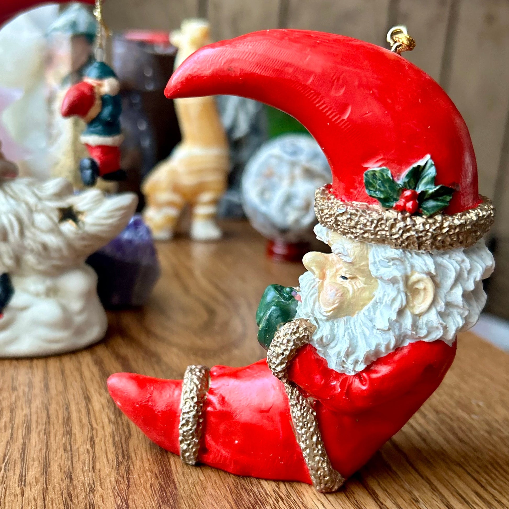 Decorative figurine of a Santa Claus-like character with a red hat and beard on a wooden surface.