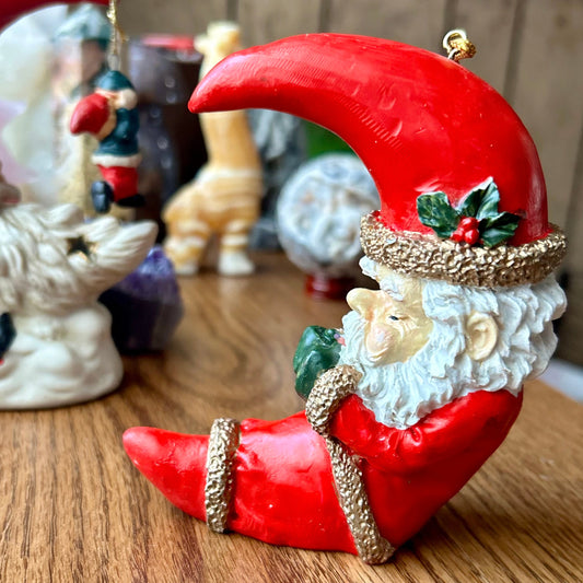 Decorative figurine of a Santa Claus-like character with a red hat and beard on a wooden surface.