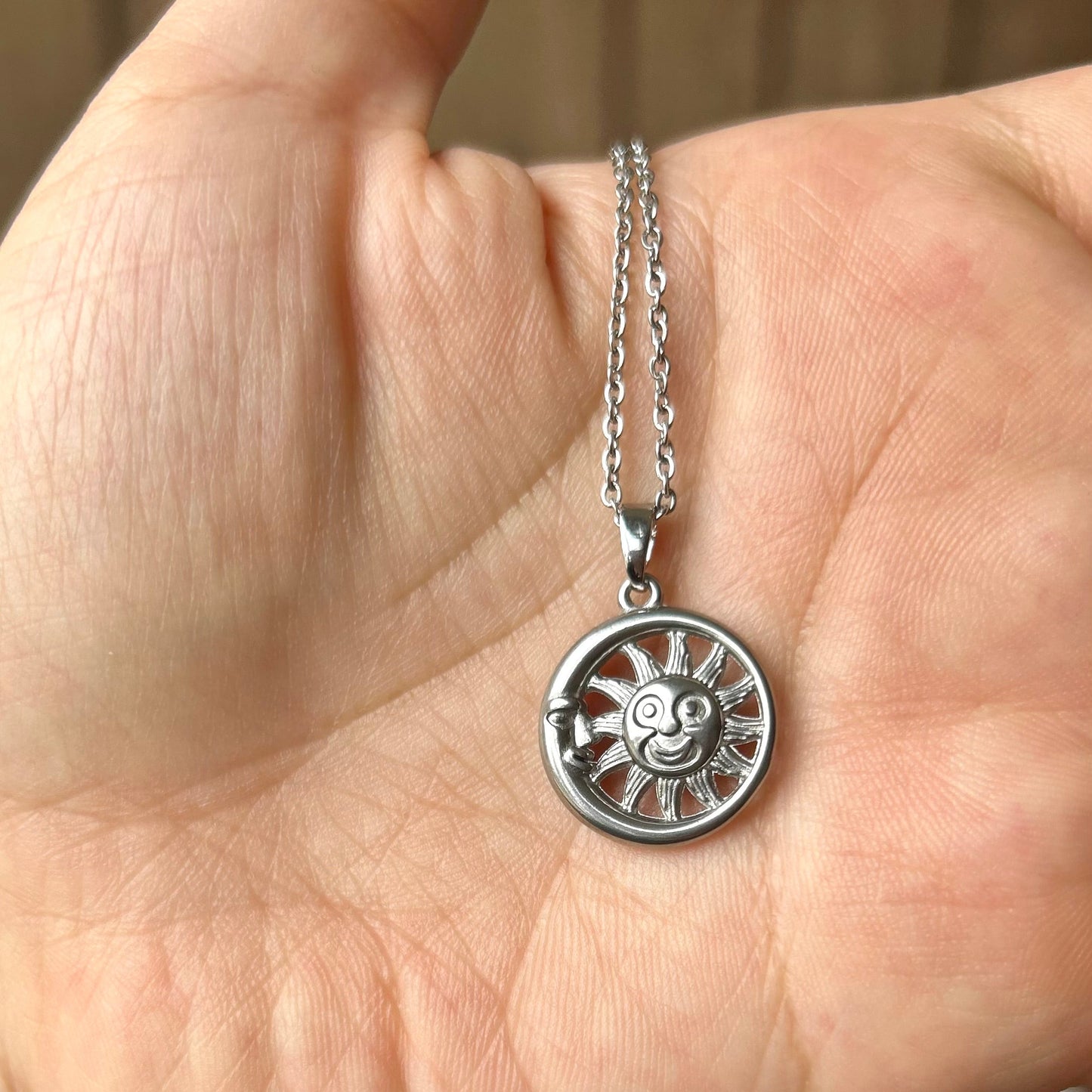 Silver necklace with a pendant held in a hand against a blurred background
