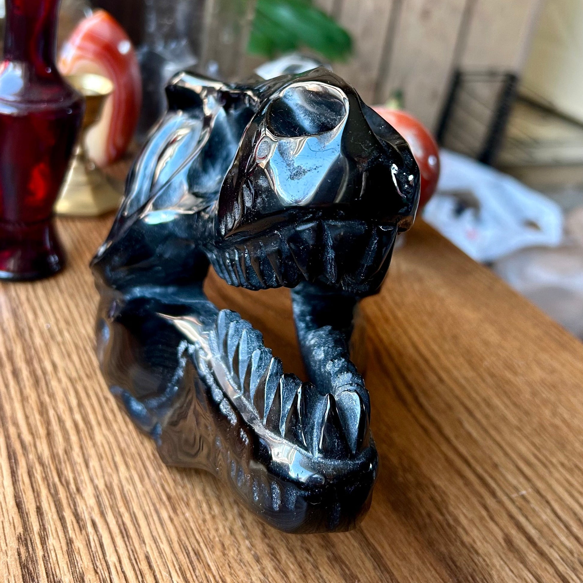 Black stone sculpture of a dragon on a wooden surface with a blurred background