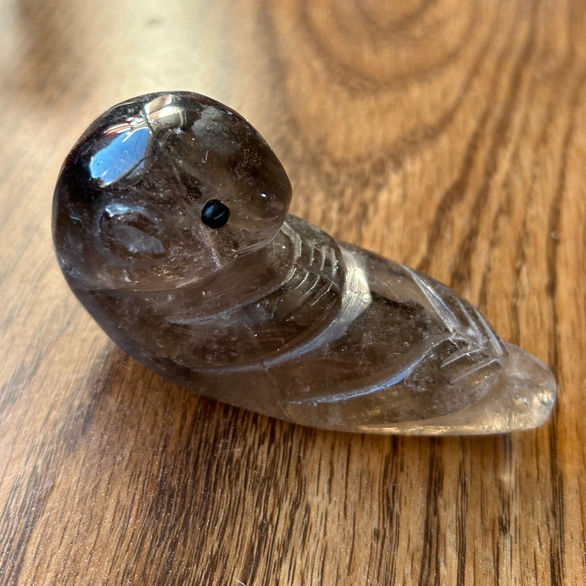 Smoky crystal bird figurine on a wooden surface