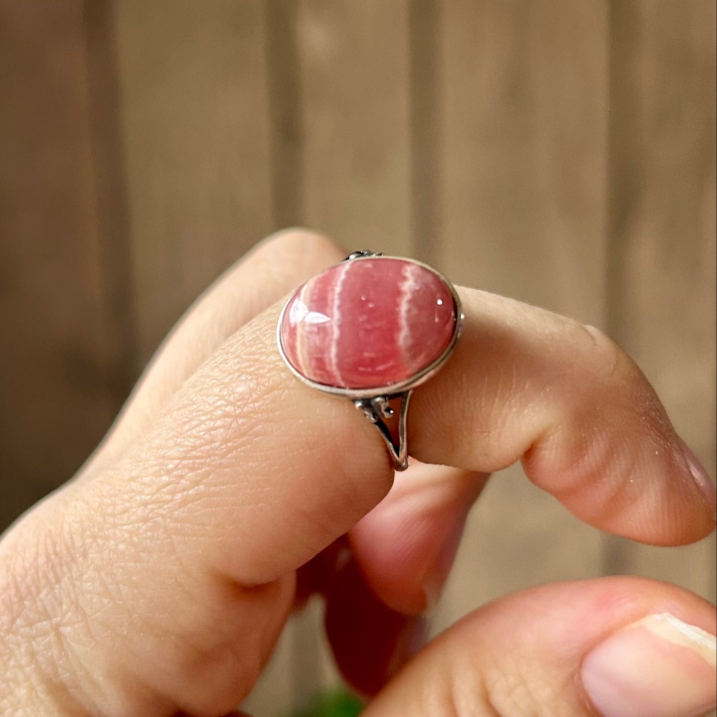 Hand wearing a ring with a pink stone against a blurred background