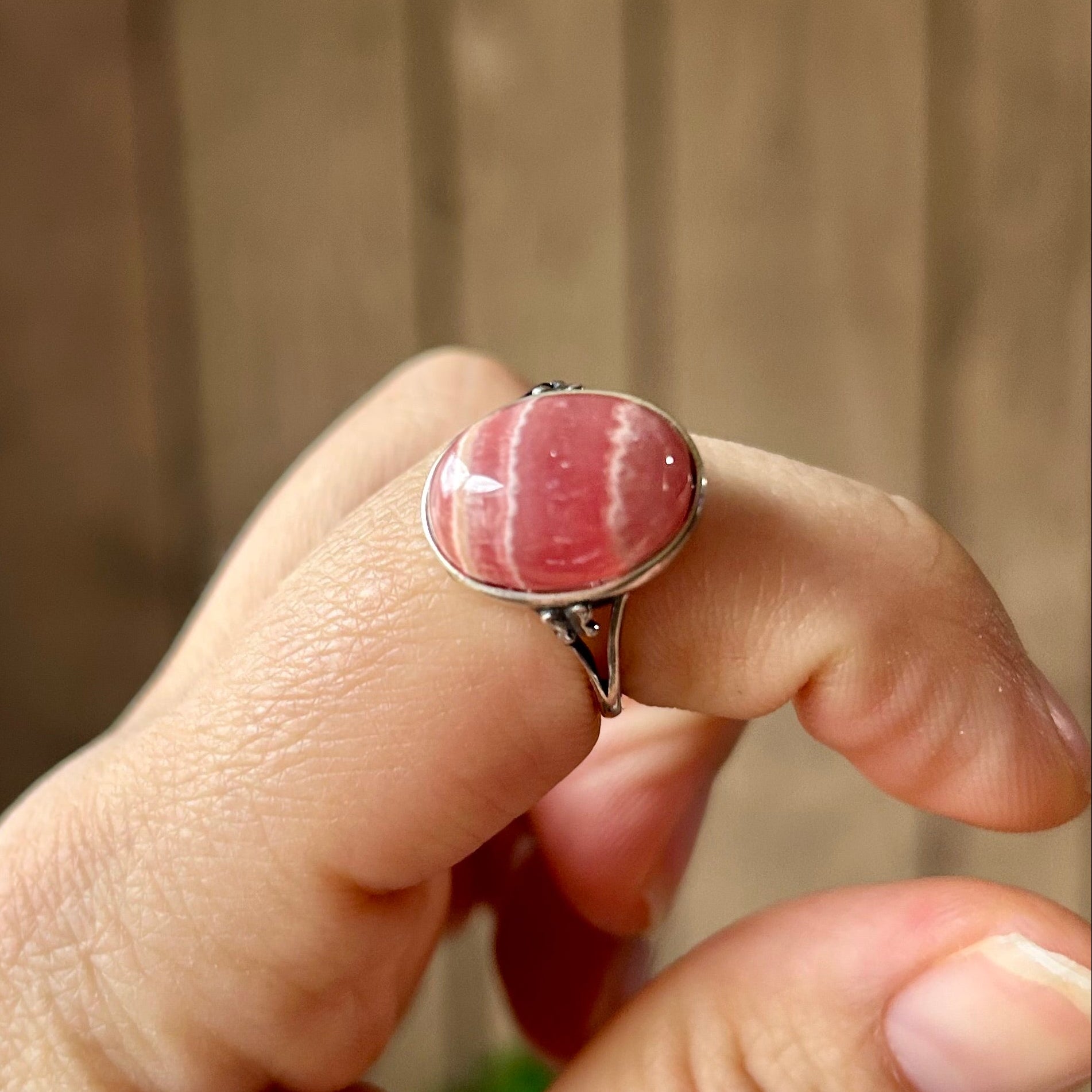 Hand wearing a ring with a pink stone against a blurred background