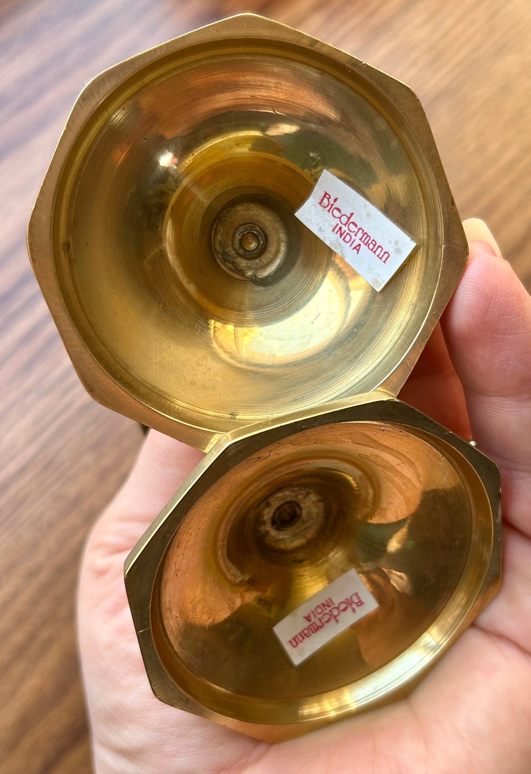 Hand holding a gold-colored object with labels on a wooden surface