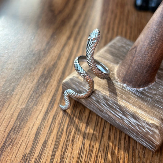 Silver snake-shaped ring on a wooden stand