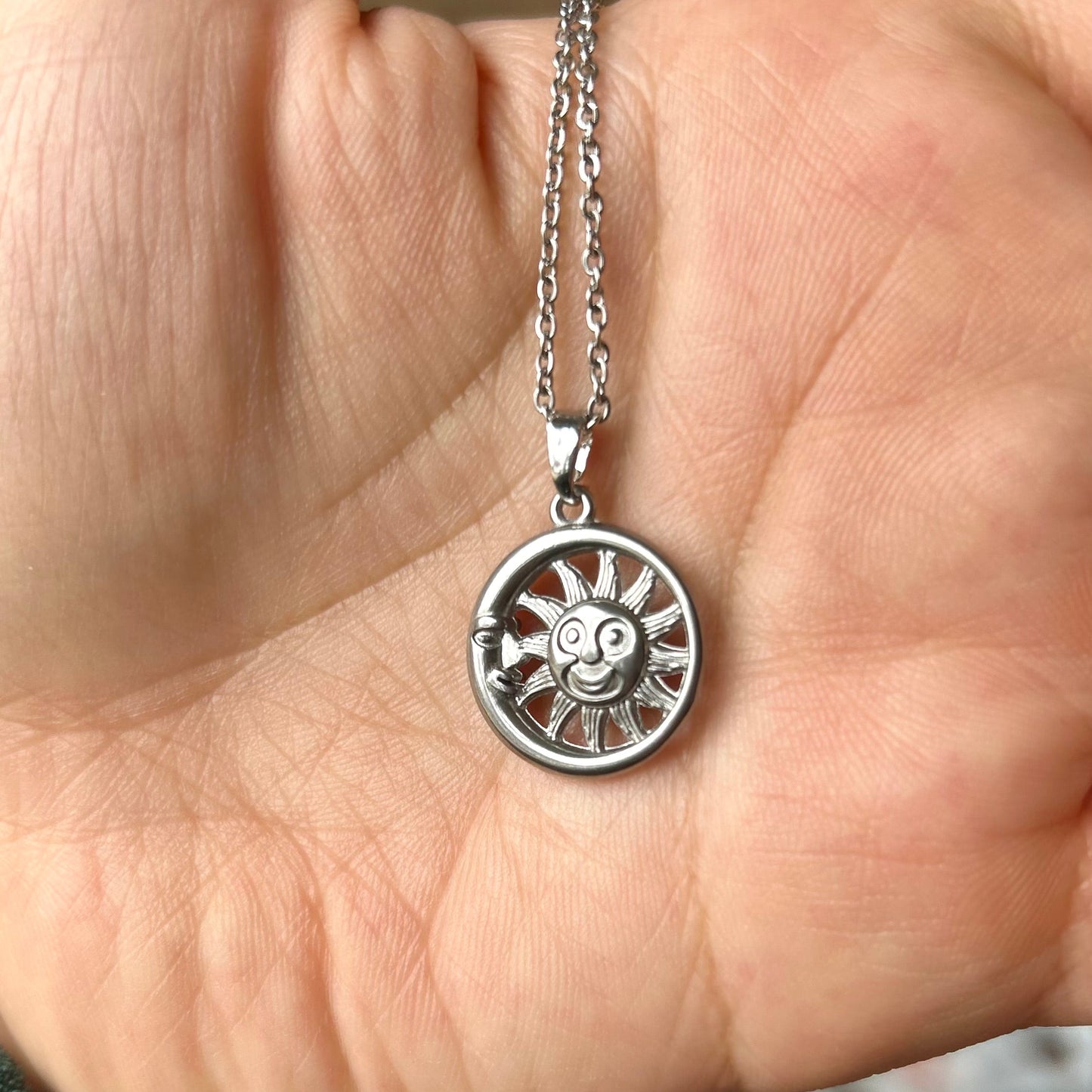 Silver necklace with a pendant held in a hand against a blurred background
