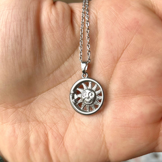 Silver necklace with a pendant held in a hand against a blurred background