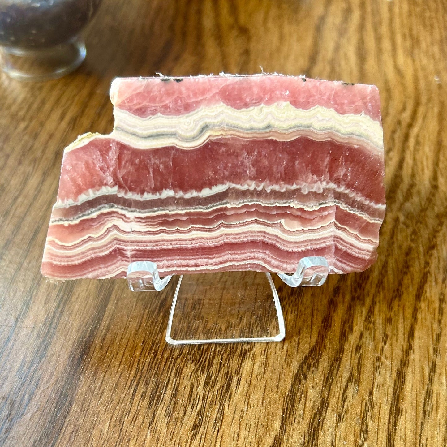 Stack of layered pink and white rock on a clear stand against a wooden background
