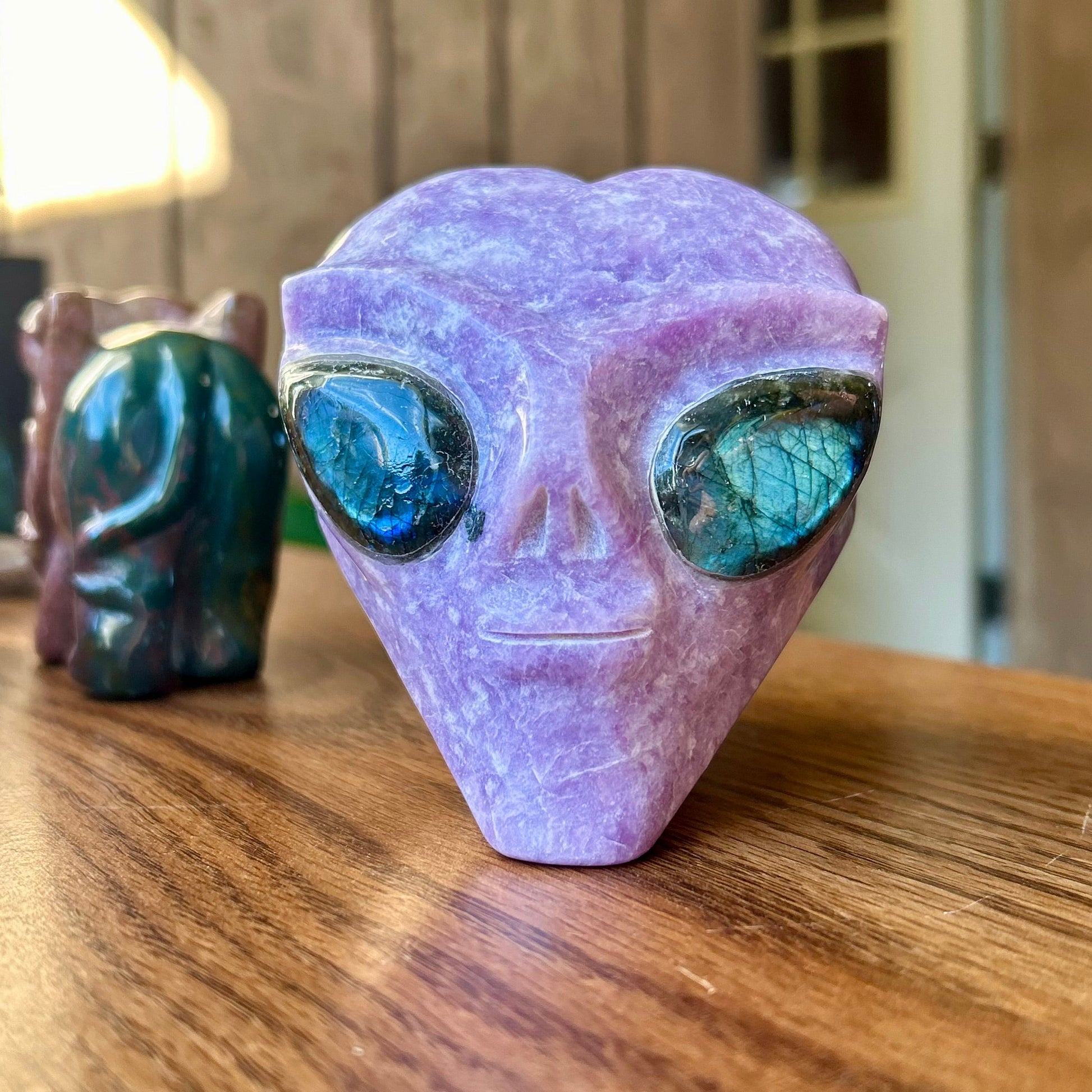 Purple alien head figurine on a wooden surface with blurred background