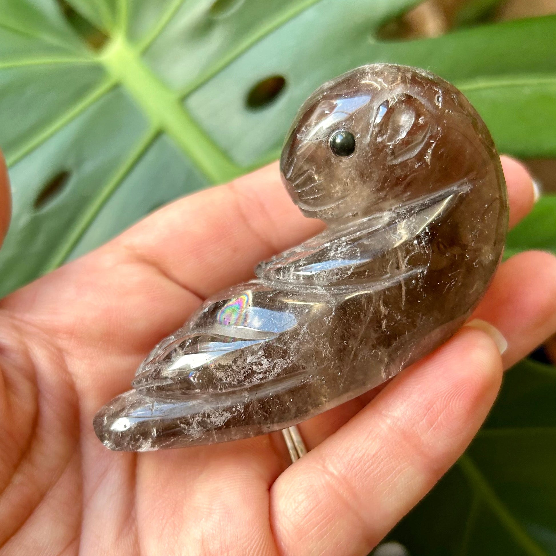 Crystal duck figurine held in a hand with green leaves in the background