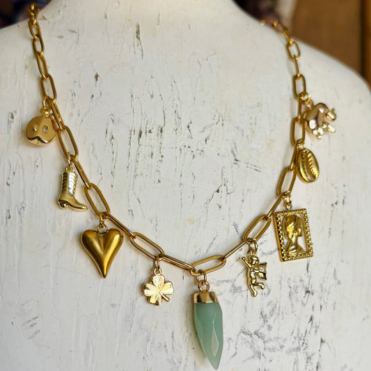 Gold necklace with various charms on a mannequin bust.