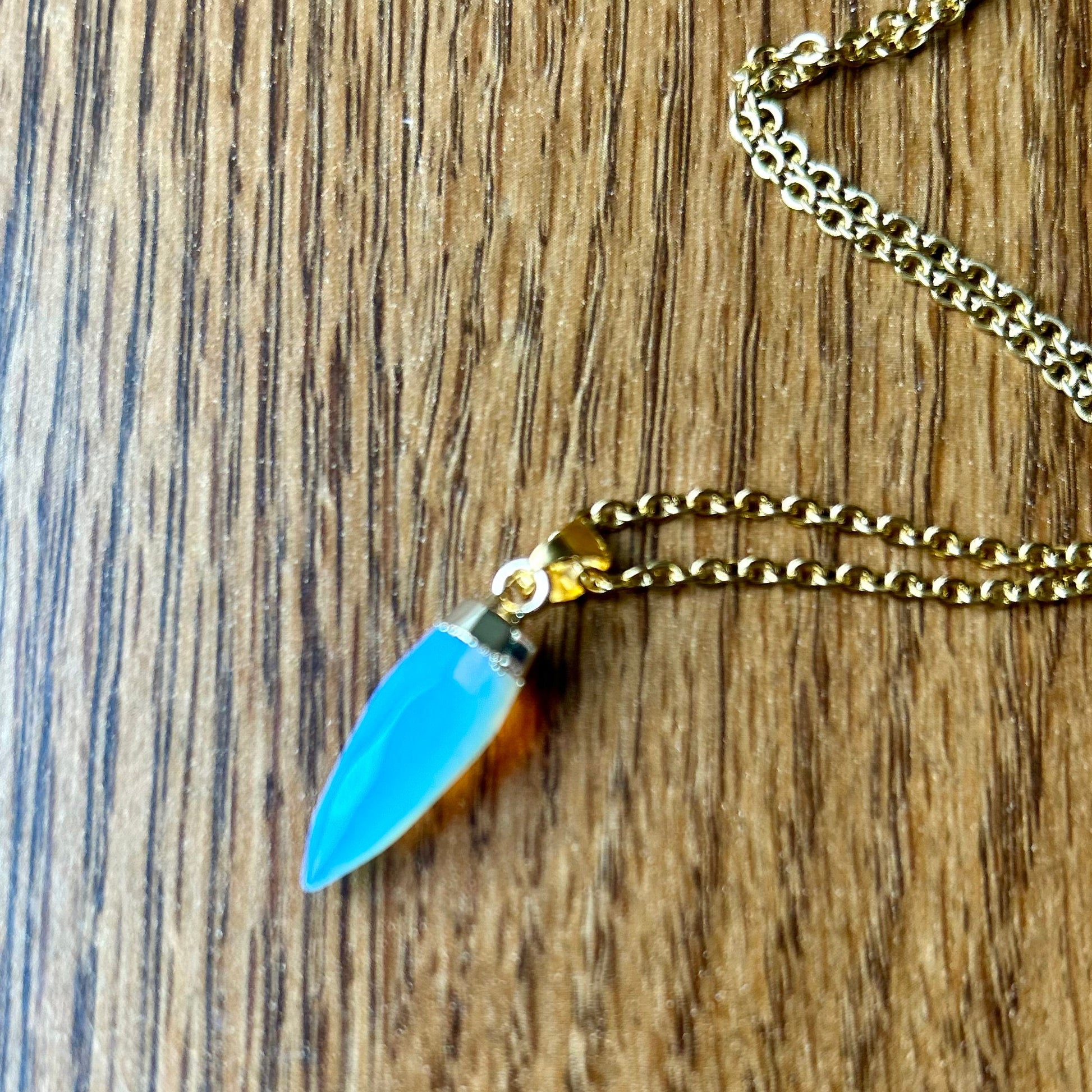 Necklace with a blue pendant on a wooden surface