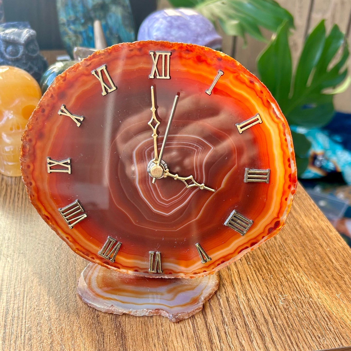 Decorative clock with a rose design on an agate-like surface, placed on a wooden surface.